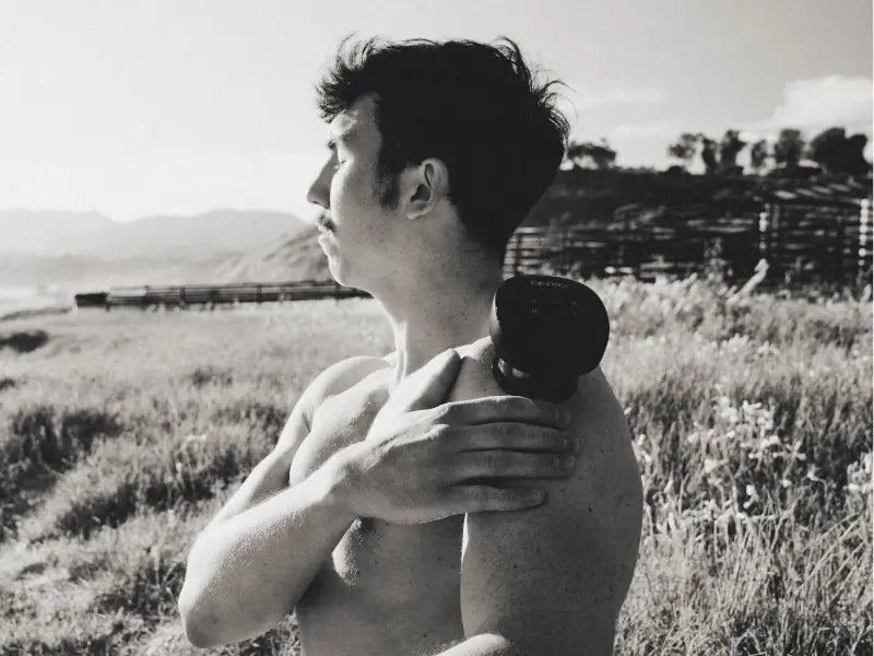 Silicone cupping therapy device placed on a man's shoulder during outdoor recovery session.