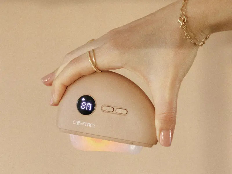 Fascia massage tool held in hand with visible LED display and soft glow.