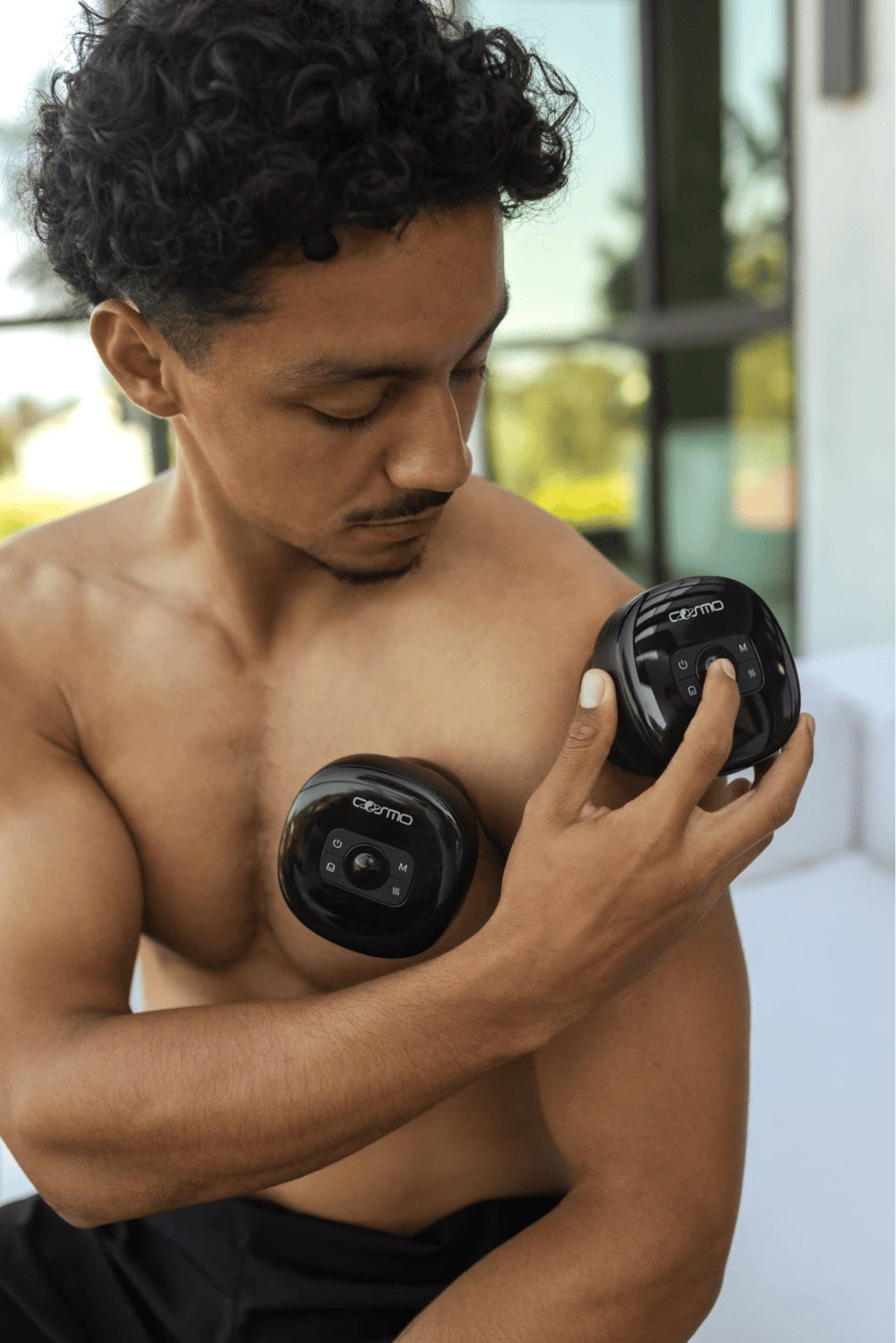 Cupping therapy device applied to a man's chest and upper arm as he adjusts the settings on the unit.