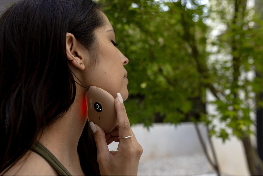 Woman using Cosmo Health electric cupping device on the neck, promoting muscle relaxation, pain relief, and lymphatic drainage during an outdoor wellness routine.